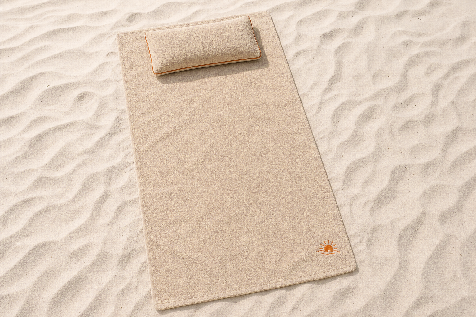 Top view of the Sun Soaker towel and pillow laid out on the sand